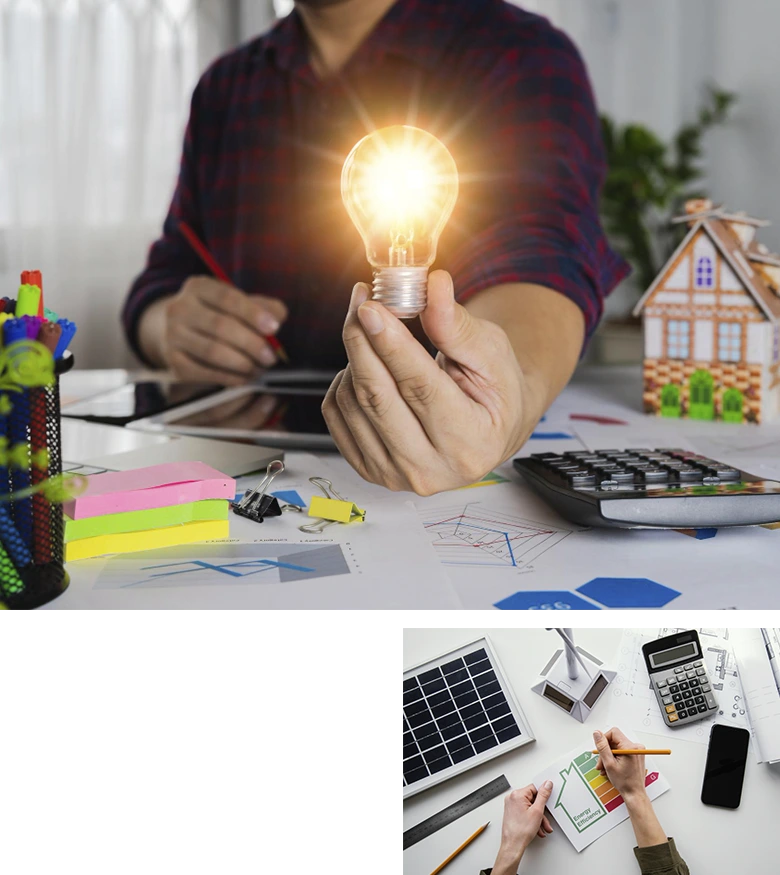 mano sujetando bombilla encendida y mesa con calculadora, portátil y móvil